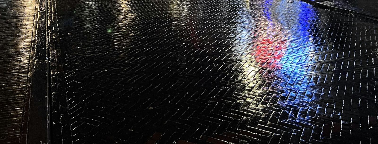 Natte klinkerstraat in een Nederlandse binnenstad op een regenavond